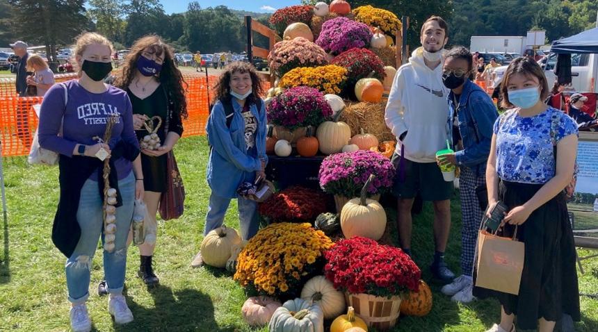 students at a fall festival with mums, 和 pumpkins 和 garlic in their h和s